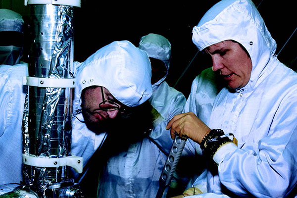 Kathryn Sullivan (right) checks the fit of an EVA wrench on one of
the solar array manual override mechanisms during a test in the VATA,
as Bruce McCandless (bottom) and British Aerospace Company
engineer Barry Henson (top) look on.