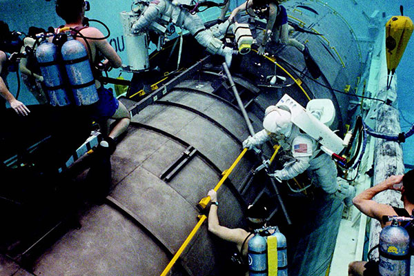 Scuba divers monitor Kathy Sullivan (spacesuited figure at right)
and Bruce McCandless (top center) as they practice EVA tasks on the
Hubble mockup in the Johnson Space Center Weightless Environment
Test Facility (WETF) during training for STS-31.